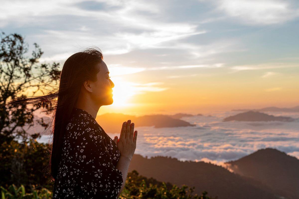 woman praying at sunrise as she chooses to trust God and not let fear and doubt steal her peace