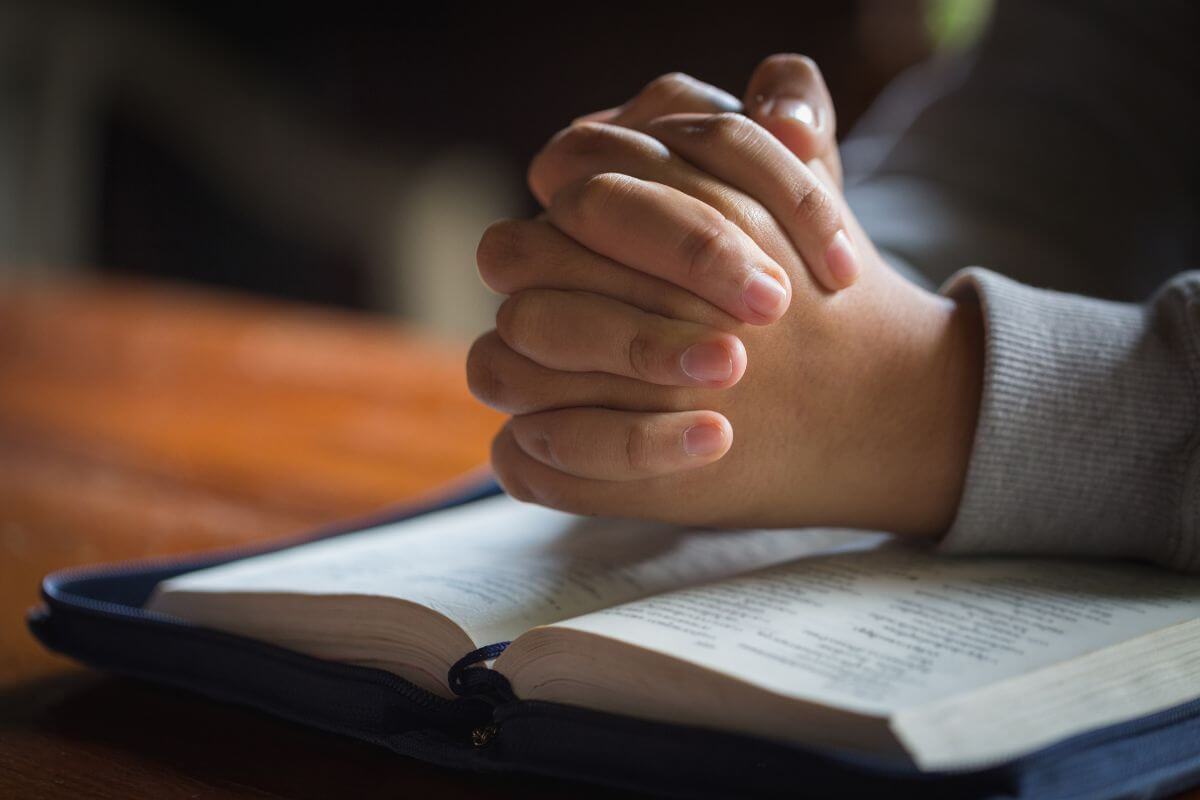 Hands clasped in prayer over open bible verses for sleepless nights