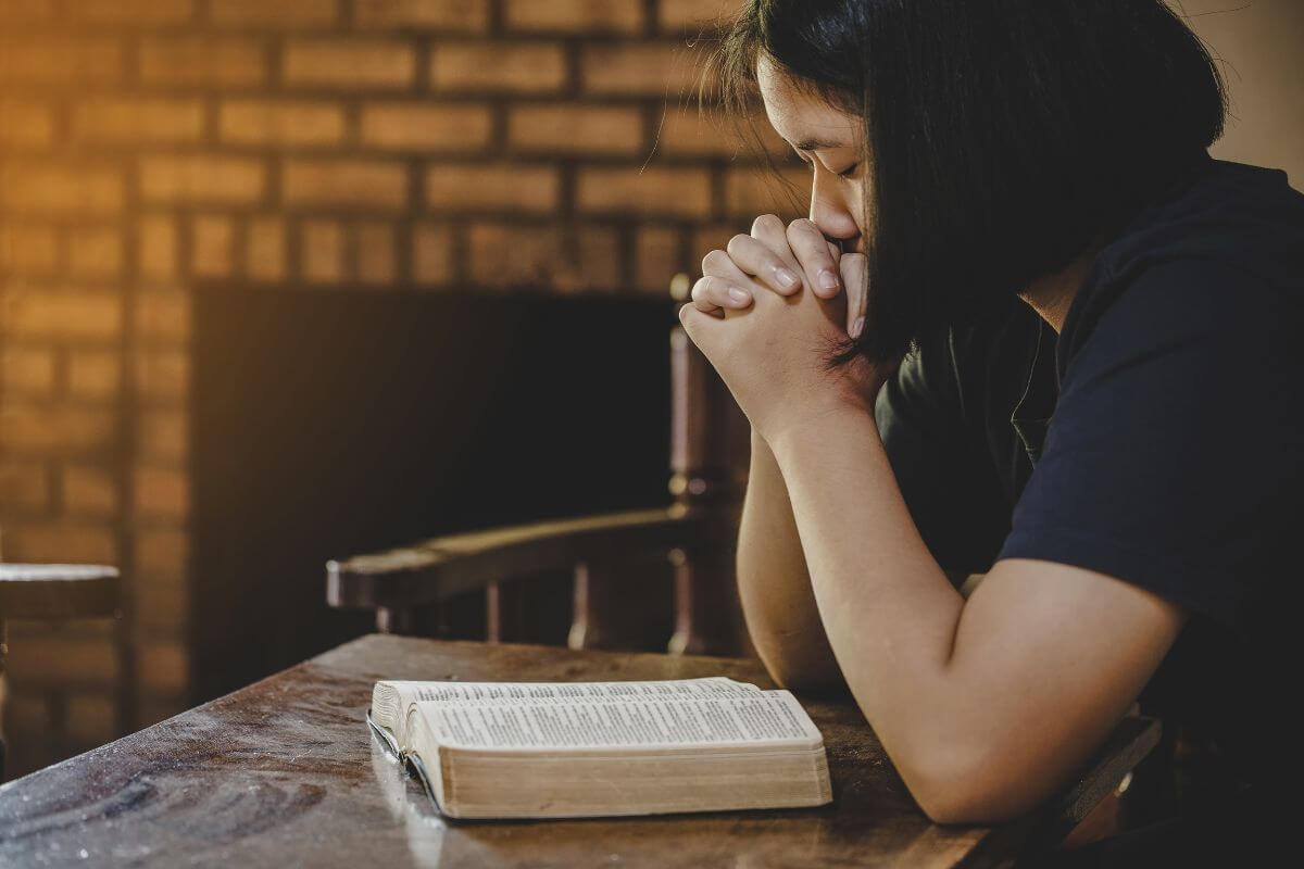 A woman praying over an open Bible as she entrusts tomorrow to God.