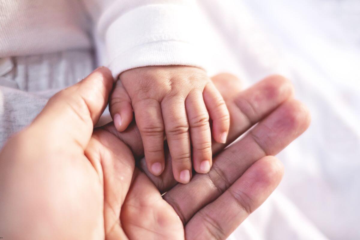 A baby's hand resting gently in a parent's hand, symbolizing how we give your worries to God and learn to rest securely in His loving care.