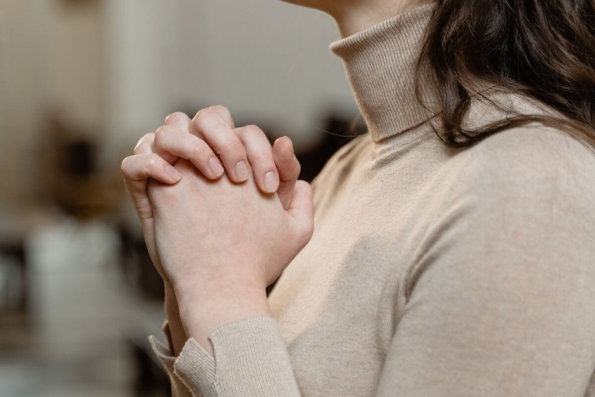 "Close-up of a person praying with folded hands in a quiet moment of faith and reflection."