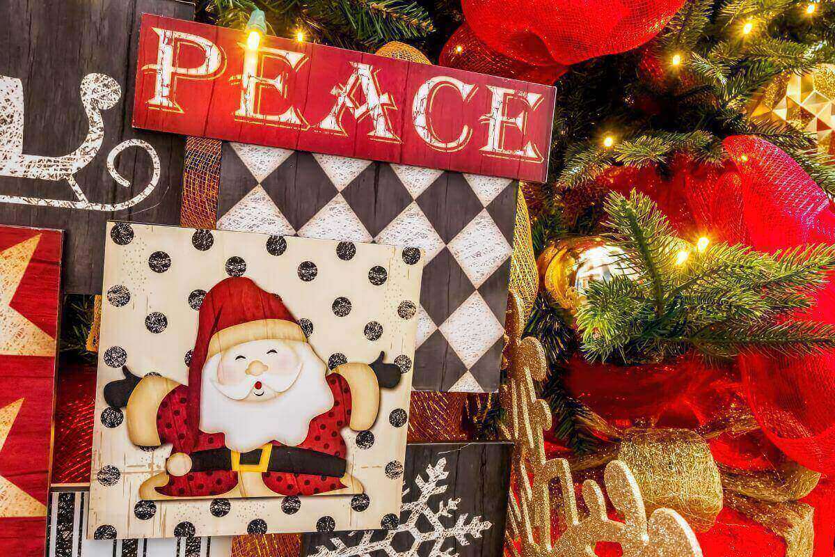 Festive Christmas decorations featuring a cheerful Santa illustration and a red wooden sign that reads “PEACE.” Surrounded by glowing lights, gold ornaments, and evergreen branches, the image evokes calm and joy, symbolizing God’s peace rising above the pressures of the holiday season.